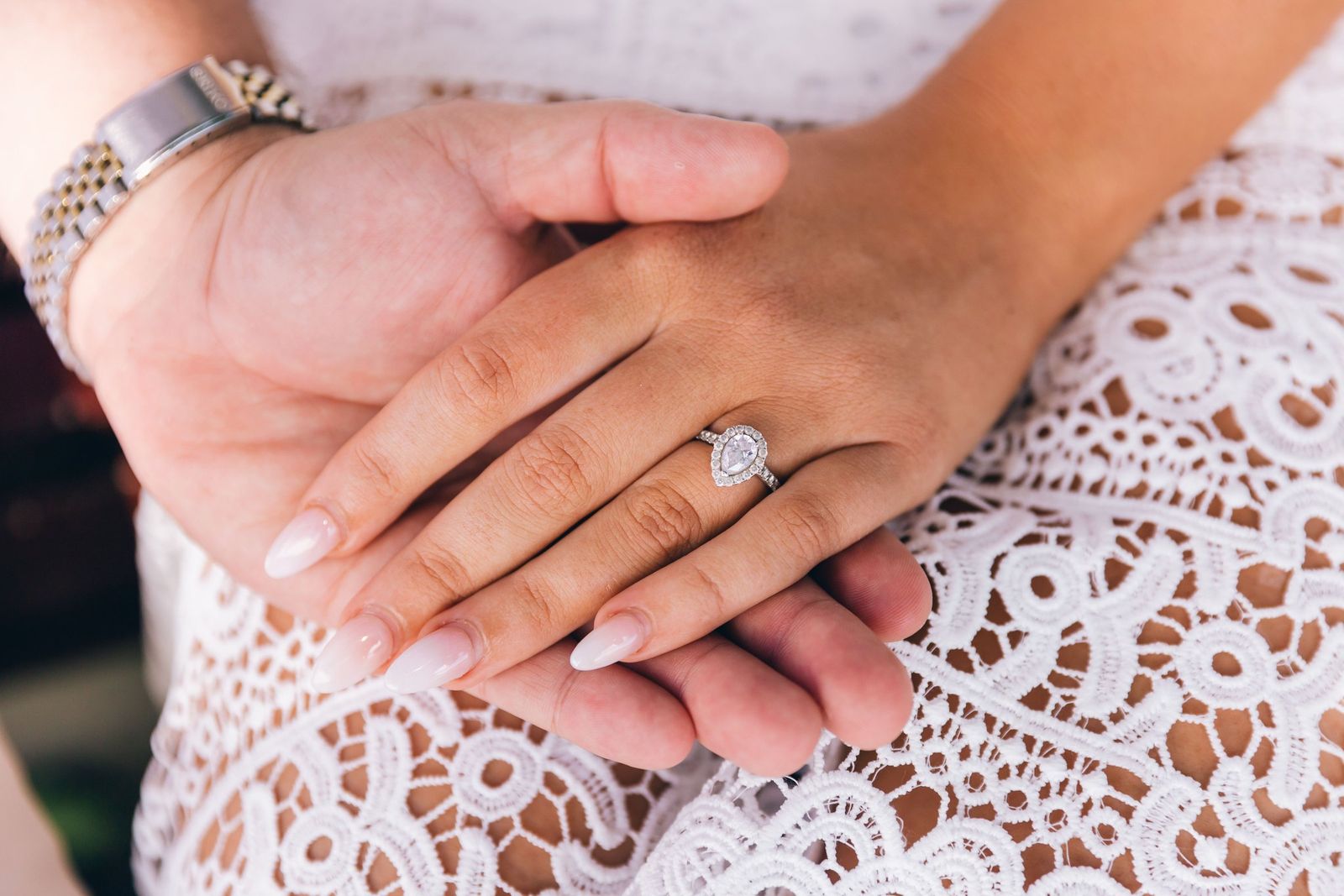 Hands resting on lace, one wearing a new ring